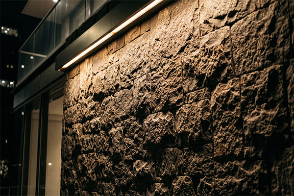 A stone wall with texture highlighted by wall grazing lights